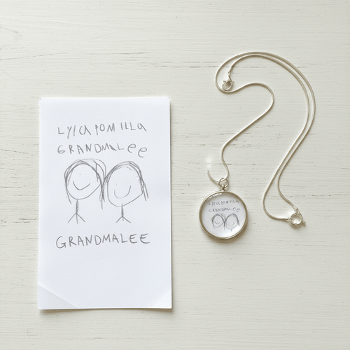 Flat lay charm necklace with child's drawing